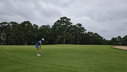 Obraz premium Woman Playing Golf on a Cloudy Day