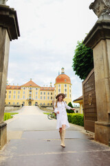 girl in a white dress, beige boots and a beige hat walk near Moritzburg Castle