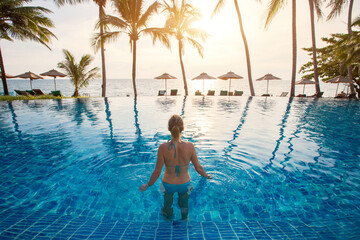 woman in beautiful swimming pool of luxury beach hotel resort