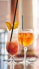 Cocktails, alcohol beverage and fruit for drink at table in a nightclub for party or event celebration. Mixology, mocktail and orange in glass with straw for refreshments in restaurant or pub