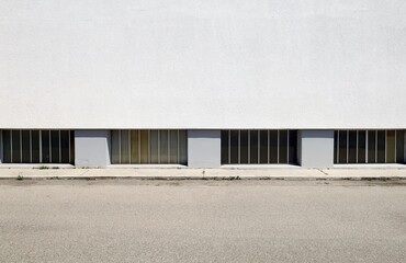 Barred basement windows on white plaster wall of residential building at the roadside . Concrete...