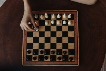 Intense strategic game of chess being played on a classic wooden table with black and white chess...