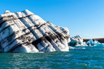 A large ice block sits in the ocean, surrounded by smaller ice blocks