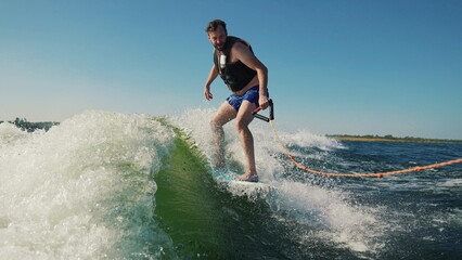A man wakeboards after a boat. Fun on the water during the hot summer on the lake. Wakeboarding....
