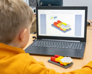 Boy in robotics class learning to make a robot with construction pieces and a laptop