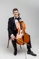 Young male artist sitting on chair and playing contrabass