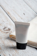 Plastic white tube for cream or lotion. Skin care or sunscreen cosmetic on white wood background.