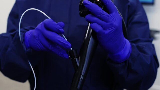 doctor with blue latex gloves preparing endoscopy equipment for procedure 60fps
