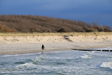 eine junge Frau geht allein am Strand spazieren