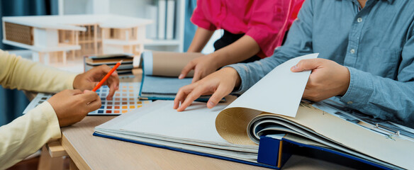 Skilled interior design team carefully selecting curtain materials while coworker selecting the...