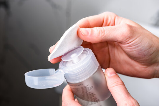 Hands of woman using toner and cotton pad.