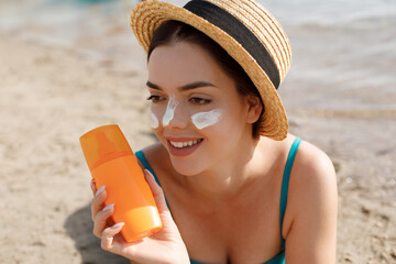 Beautiful woman applying cream sunscreen on tanned face. Sunscreen. Skin and body care. The girl...