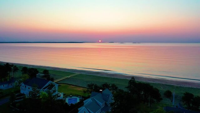 Beautiful Beach Sunset in Saco Maine with Colors Reflecting off Ocean Waves and Vacation Homes Along the New England Atlantic Coastline. Aerial Drone View of Colorful Golder Hour Sky and Sea Water