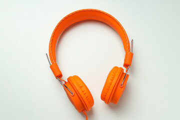 On-top, large, bright orange headphones, on a light background.