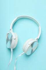 White, over-the-ear headphones with a wire on a blue background.