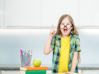 Surprised young girl wearing eyeglasses showing finger up has idea. Success, idea and creative...