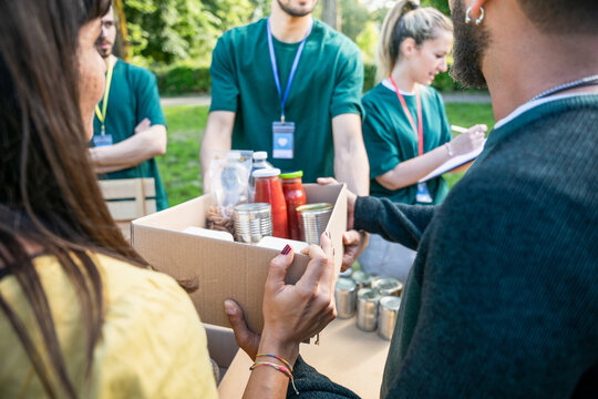 Food bank - Group of volunteers in uniform prepare boxes of basic necessities to donate them to people in need