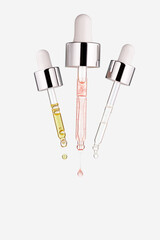 Three transparent glass pipettes with cosmetics on a white background. Skin care product
