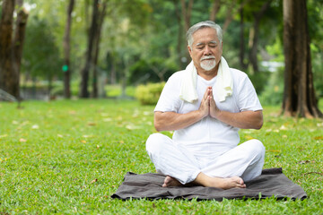 asian senior man meditating and doing yoga in the park