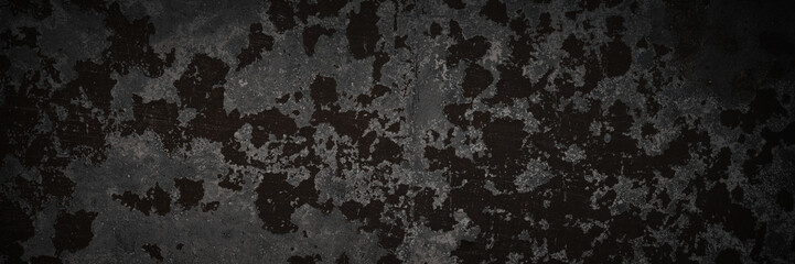 Dark wide panoramic background. Peeling paint on a concrete wall. Dark grunge texture of old cracked flaking paint. Weathered rough painted surface. Patterns of cracks. Darkness background for design.