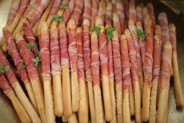 Array of breadsticks wrapped in bacon with a garnish of green leaves