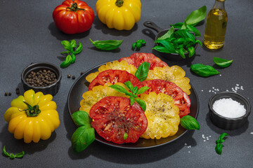 Colorful Heirloom tomato harvest. Ripe ribbed vegetables with fresh basil leaves. Wooden background
