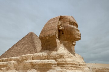 Majestic sphinx sculpture stands guard in front of the iconic pyramids of Giza, Egypt.