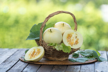 White Musk Melon on blurred greenery background, Chinese melon fruit in Bamboo mat on wooden table...
