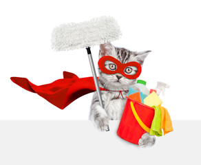 Cute kitten wearing superhero costume holds bucket with washing fluids and swab above blank white banner. Isolated on white background
