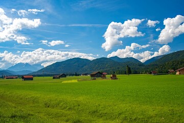 Scenic Alpine landscape with a green field and rural houses in the distance. Upper Bavaria, Germany