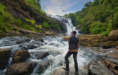 Hiker observing a waterfall in Sri Lanka