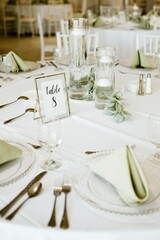 Elegant white table setting for a wedding reception with pristine plates and napkins