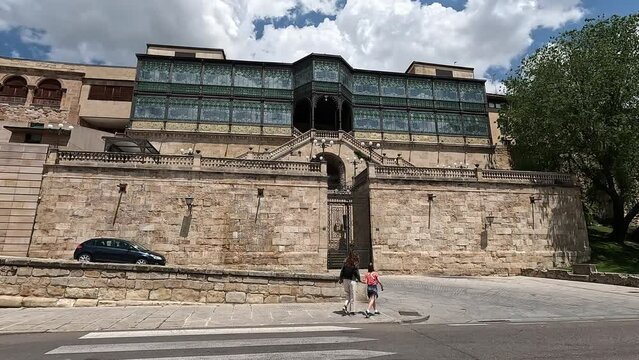 Woman and girl from behind crossing a pedestrian crossing with the facade of the iconic Casa Lis building in Salamanca, Castilla y Leon, Spain