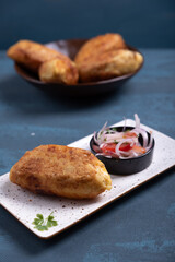 Close-up of crispy potatoes stuffed with savory delights and a salad on the side.