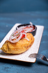 Delicious Peruvian stuffed potato on a plate with a salad on top.