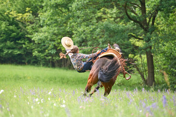 Cowgirl falls from a bucking horse