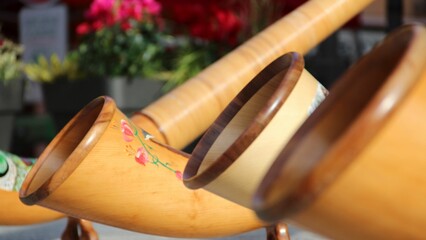 there is a plant and three wooden drums with handles near a vase