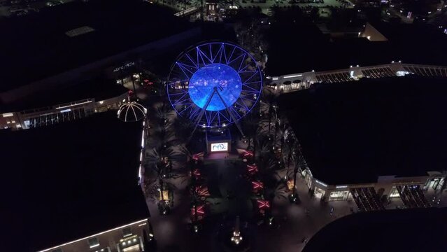Drone footage of the Irvine Spectrum Center Giant Wheel illuminated at night in Irvine, California