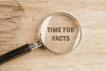 Time for facts message written visible through a magnifying glass on an old faded background