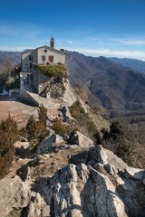 a steep cliff overlooking the mountains at an old church on top of a mountain