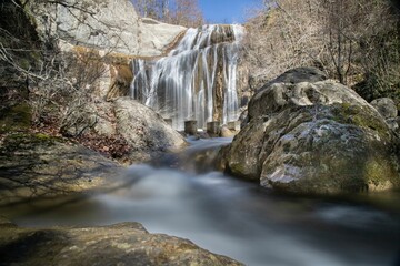 a waterfall cascades over rocks in a river surrounded by forest