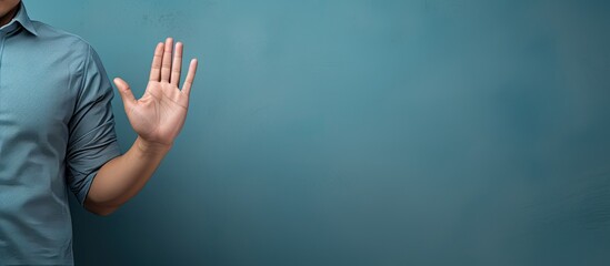 Handsome Asian man wearing blue shirt with hand gesture pose of stop or prohibition with copy space
