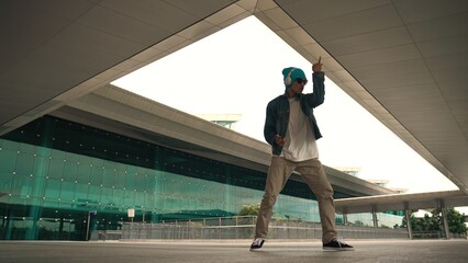 Motion shot of happy hipster practice b boy dance with stylish cloth at building. Dancer enjoy show...