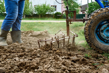 Man cultivating soil with tiller block in spring.