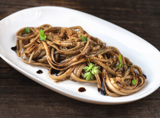  Black fermented garlic linguine pasta with  fermented garlic sauce and dry grated bread. A simple recipe in 10 minutes. Modern recipes for Italian pasta, gourmet soft taste. Rustic style, front view
