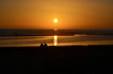 Obraz premium Picturesque scene of a waterfront park at sunset with a family seated on a bench enjoying the view