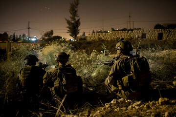 soldiers crouching on a rescue mission in the middle of the bushes at night, desert