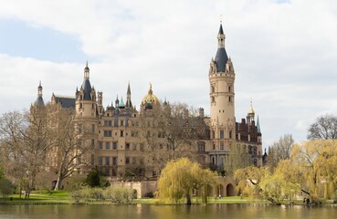 Obraz premium Majestic Schwerin Castle situated on an idyllic lake, surrounded by lush foliage in Burggarten