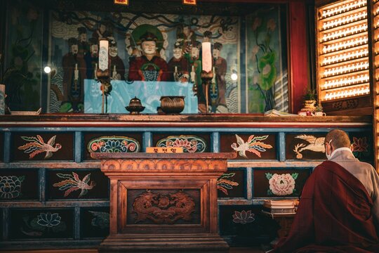 Buddhist monk in traditional saffron robes are seen in a shrine, bowing in prayer and contemplation