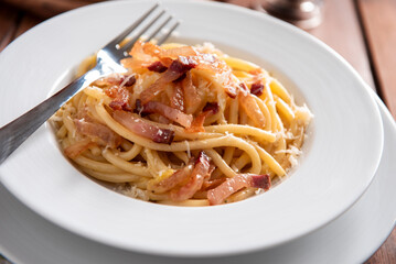 Piatto di deliziosi bucatini alla gricia, ricetta tradizionale di pasta con guanciale, pecorino e pepe nero della cucina Romana, pasta italiana, cibo europeo 
